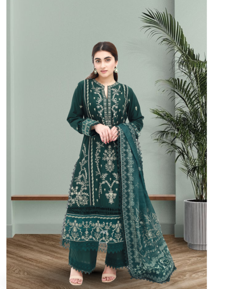  Daiselle Woman wearing a green embroidered traditional outfit in a room with a plant.